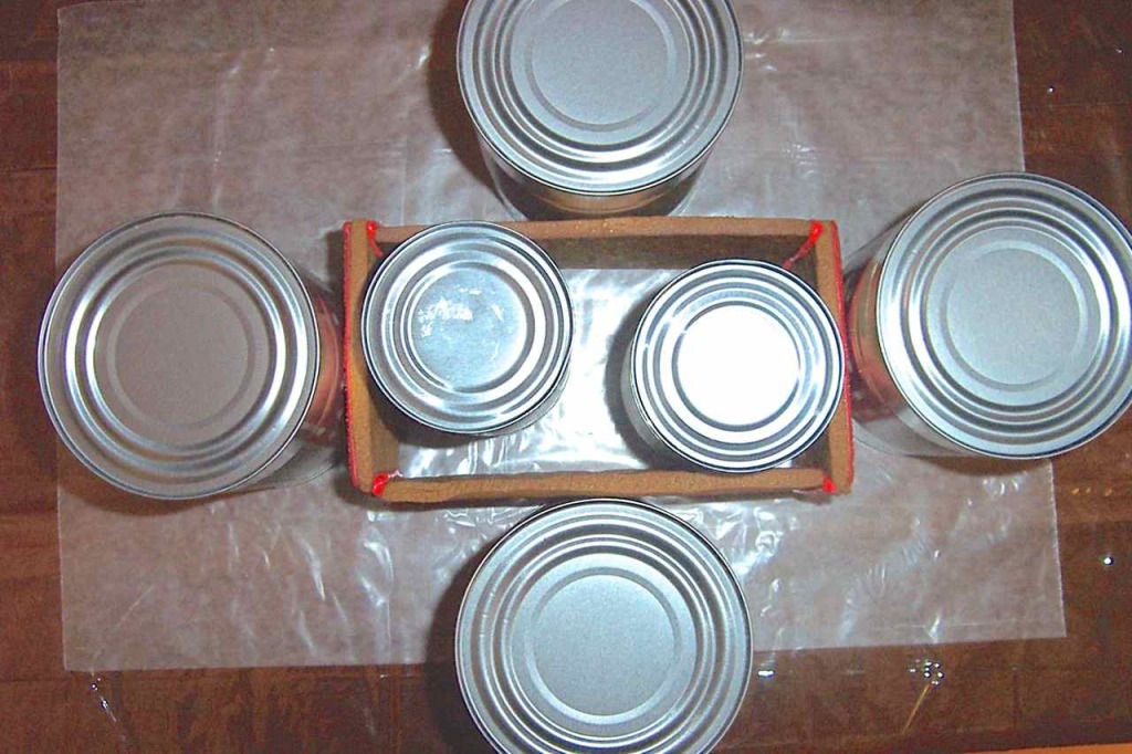 Showing aluminum cans holding the glued sides of box in place for drying.