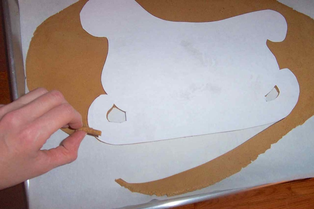 Peeling the excess dough away from the cut-out template. 