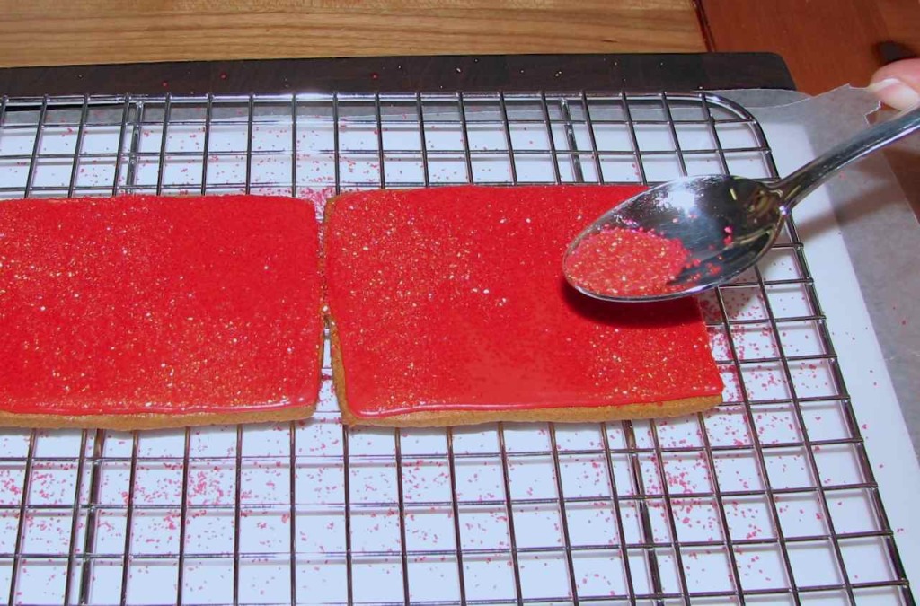 A picture of the front and the back of Santa's Sleigh "box" while the sugar is being sprinkled over the wet flood icing. 