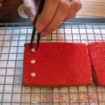 Sugar snowflakes being added with a tweezer to the still-wet, flooded and sugared box panels.