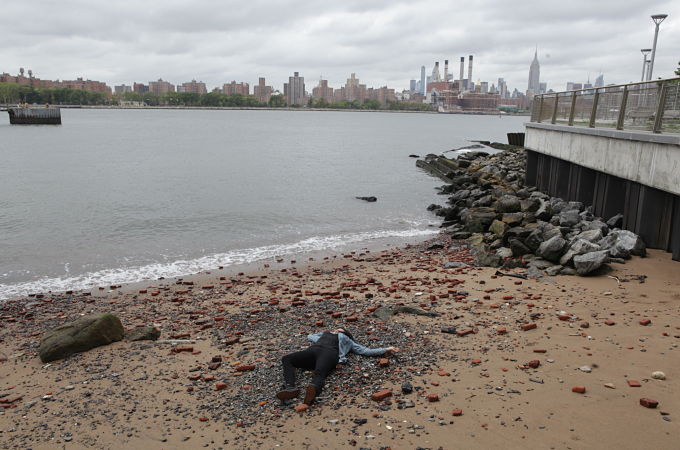 Beach scene from Pretty Dead with faux dead body and NYC in the background.